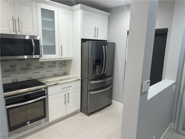 8241 Pacific Beach Dr, Fort Myers, FL 33966 - kitchen with appliances with stainless steel finishes, decorative backsplash, white cabinetry, glass insert cabinets, and light stone counters