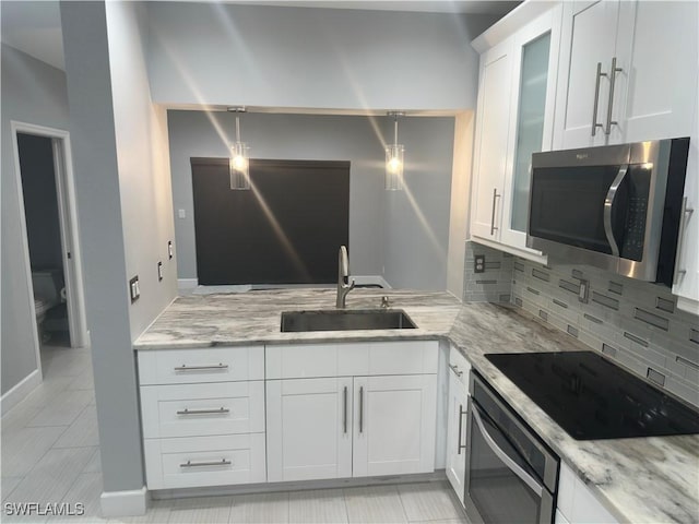8241 Pacific Beach Dr, Fort Myers, FL 33966 - kitchen with appliances with stainless steel finishes, backsplash, white cabinets, light stone counters, and glass insert cabinets