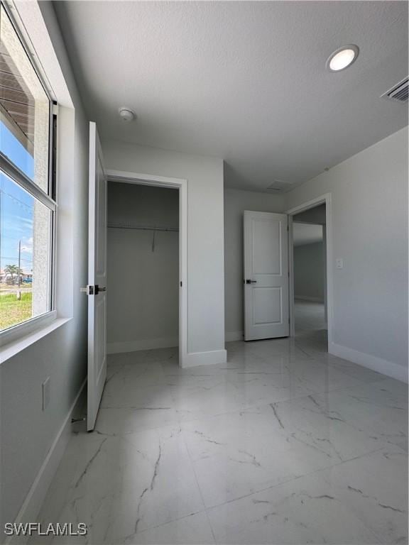 2902 27th St SW, Lehigh Acres, FL 33976 - unfurnished bedroom featuring light marble finish floors, a closet, recessed lighting, and a textured ceiling