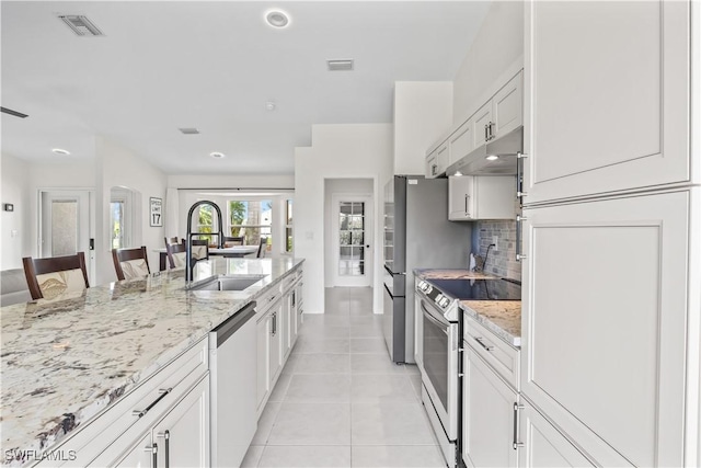 22 NW 14th Ave, Cape Coral, FL 33993 - kitchen featuring stainless steel appliances, under cabinet range hood, light tile patterned floors, light stone counters, and a kitchen breakfast bar