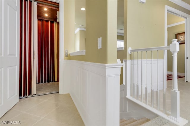 713 Regency Reserve Cir Unit 5903, Naples, FL 34119 - hall featuring an upstairs landing, elevator, light tile patterned floors, wainscoting, and a decorative wall
