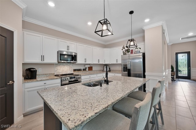 17573 Ashcomb Way, Estero, FL 33928 - kitchen with stainless steel appliances, white cabinets, an island with sink, a breakfast bar area, and crown molding