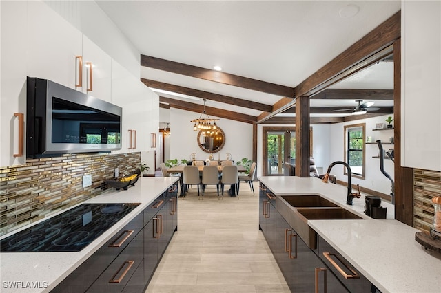 3270 14th Ave NE, Naples, FL 34120 - kitchen with stainless steel microwave, black electric cooktop, tasteful backsplash, white cabinets, and hanging light fixtures