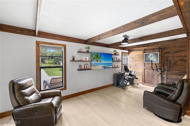 3270 14th Ave NE, Naples, FL 34120 - living area featuring beam ceiling, a barn door, light wood-style flooring, a ceiling fan, and wood walls