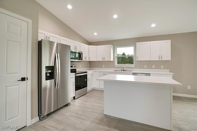 3010 62nd St W, Lehigh Acres, FL 33971 - kitchen featuring appliances with stainless steel finishes, light countertops, lofted ceiling, a center island, and white cabinetry