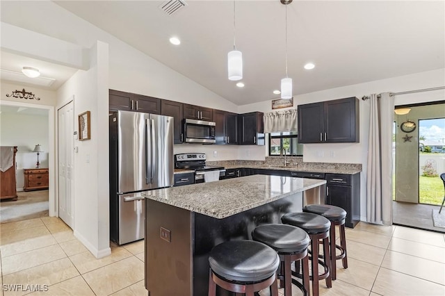 2619 42nd St SW, Lehigh Acres, FL 33976 - kitchen with stainless steel appliances, light tile patterned flooring, vaulted ceiling, light stone countertops, and a center island