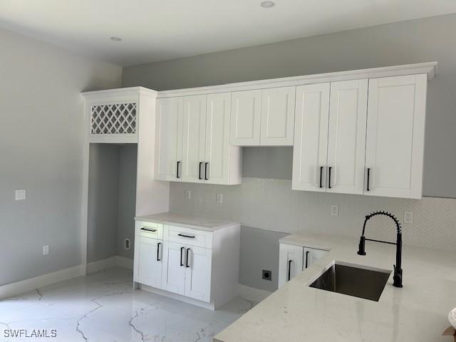 3501 E 10th St, Lehigh Acres, FL 33972 - kitchen featuring light marble finish floors, tasteful backsplash, white cabinets, and light stone counters
