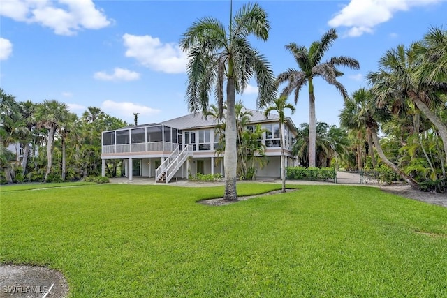 6120 Henderson Rd, Sanibel, FL 33957 - rear view of property featuring a sunroom, stairs, and a lawn