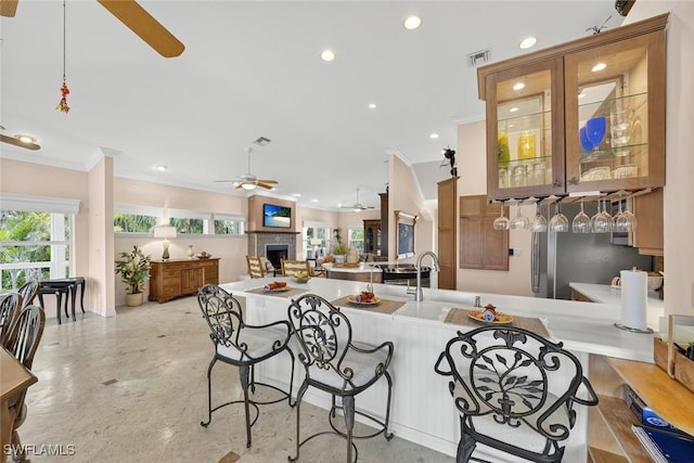 6120 Henderson Rd, Sanibel, FL 33957 - kitchen featuring a ceiling fan, crown molding, a peninsula, a kitchen bar, and recessed lighting