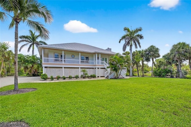 6120 Henderson Rd, Sanibel, FL 33957 - raised beach house featuring a porch, a front yard, stairway, and a metal roof