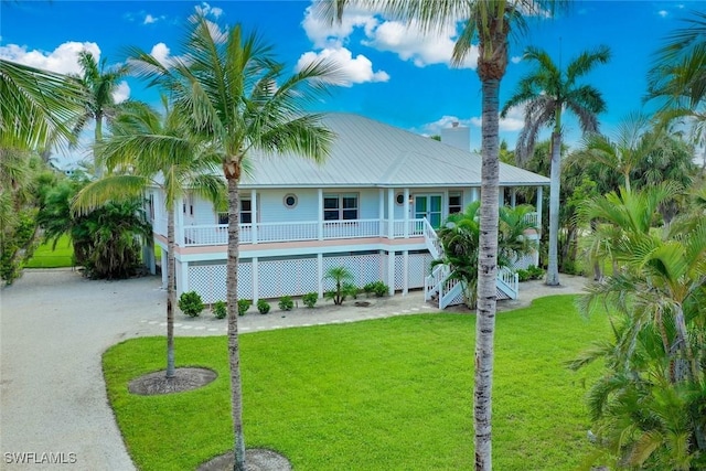 6120 Henderson Rd, Sanibel, FL 33957 - raised beach house featuring covered porch, a front lawn, stairway, a chimney, and a metal roof