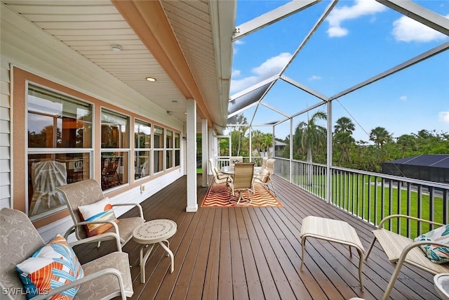 6120 Henderson Rd, Sanibel, FL 33957 - wooden deck with outdoor dining area, a lawn, and glass enclosure