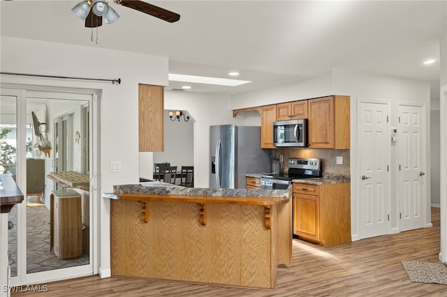 19897 Midway Blvd, Port Charlotte, FL 33948 - kitchen with appliances with stainless steel finishes, light wood-type flooring, a breakfast bar, a ceiling fan, and tasteful backsplash