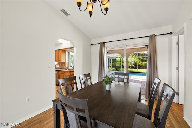 19897 Midway Blvd, Port Charlotte, FL 33948 - dining space featuring lofted ceiling, a chandelier, light wood-style flooring, and arched walkways