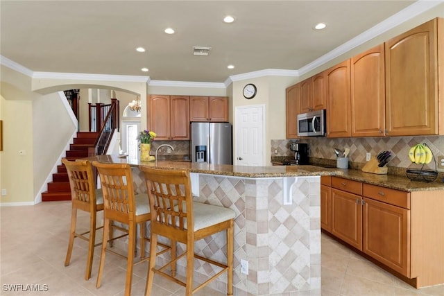 5730 Lago Villaggio Way, Naples, FL 34104 - kitchen featuring stainless steel appliances, arched walkways, a kitchen bar, ornamental molding, and stone counters