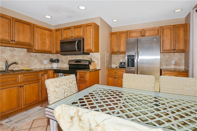 770 93rd Ave N, Naples, FL 34108 - kitchen with appliances with stainless steel finishes, stone countertops, decorative backsplash, brown cabinets, and light tile patterned flooring