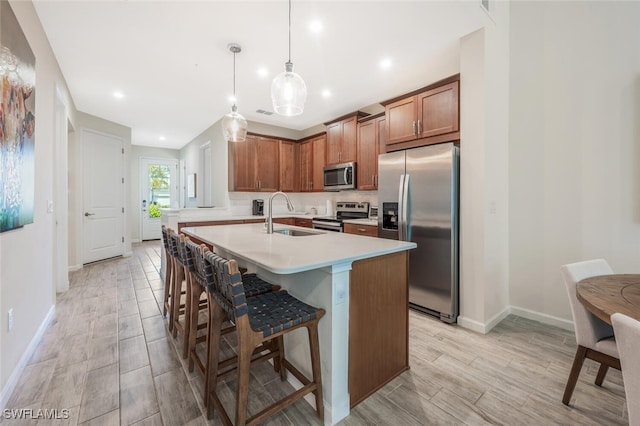 4720 Arboretum Cir Unit 102, Naples, FL 34112 - kitchen with stainless steel appliances, light countertops, an island with sink, a kitchen breakfast bar, and brown cabinetry