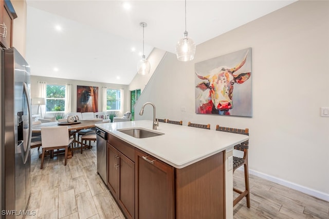 4720 Arboretum Cir Unit 102, Naples, FL 34112 - kitchen featuring appliances with stainless steel finishes, light countertops, a center island with sink, a breakfast bar area, and hanging light fixtures