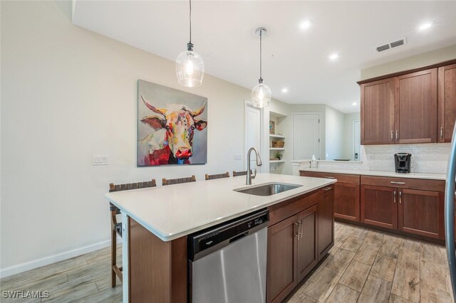 4720 Arboretum Cir Unit 102, Naples, FL 34112 - kitchen with stainless steel dishwasher, light wood finished floors, light countertops, pendant lighting, and an island with sink