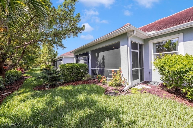4720 Arboretum Cir Unit 102, Naples, FL 34112 - view of home's exterior featuring stucco siding, a sunroom, and a yard