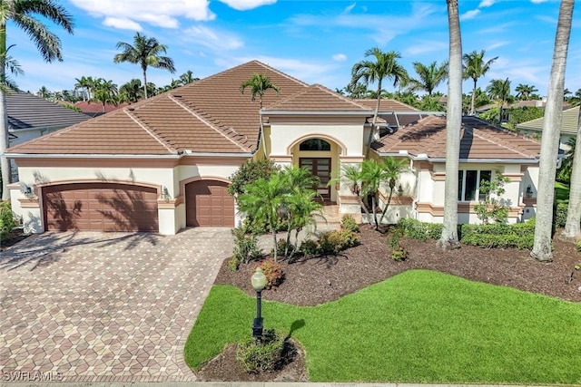 14581 Headwater Bay Ln, Fort Myers, FL 33908 - mediterranean / spanish-style home with stucco siding, an attached garage, decorative driveway, a tile roof, and a front lawn