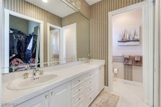 14581 Headwater Bay Ln, Fort Myers, FL 33908 - bathroom with wallpapered walls, double vanity, a spacious closet, and tile patterned floors