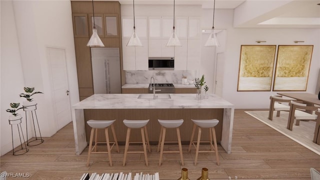 1021 Gaucho Ter, North Port, FL 34286 - kitchen featuring built in appliances, white cabinets, light wood finished floors, a breakfast bar, and a kitchen island with sink