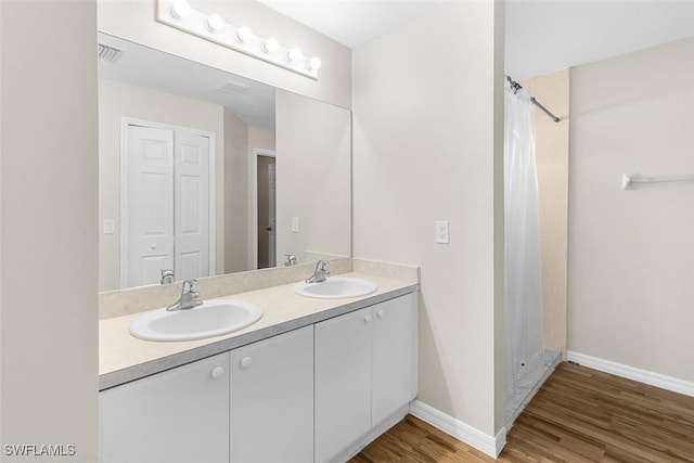2811 44th St W, Lehigh Acres, FL 33971 - bathroom with double vanity, wood finished floors, and curtained shower