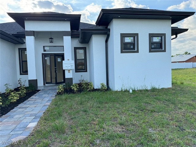 707 NE Juanita Place, Cape Coral, FL 33909 - view of front of house featuring a front yard, stucco siding, and a shingled roof
