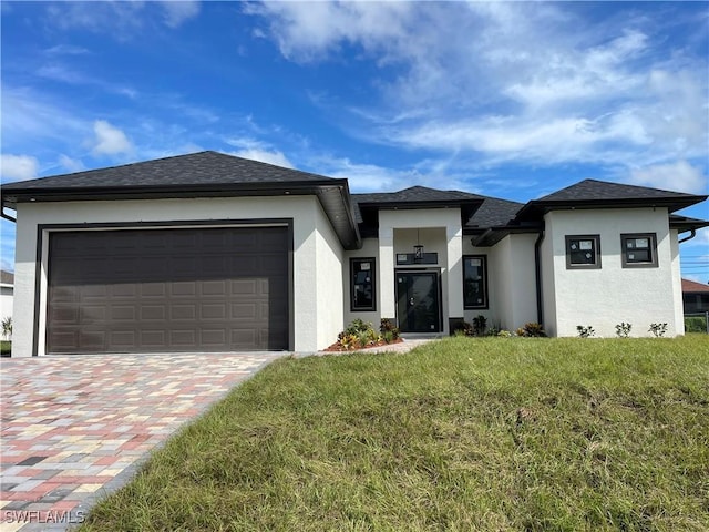 707 NE Juanita Place, Cape Coral, FL 33909 - prairie-style house with stucco siding, a front lawn, driveway, a garage, and a shingled roof