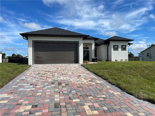 707 NE Juanita Place, Cape Coral, FL 33909 - prairie-style house featuring stucco siding, decorative driveway, a front yard, and an attached garage