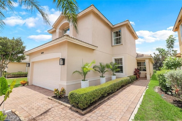 10490 Spruce Pine Ct, Fort Myers, FL 33913 - view of property exterior with stucco siding, a tiled roof, a garage, and decorative driveway