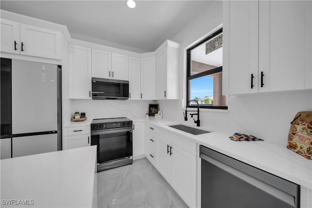 2018 Nelson Rd N, Cape Coral, FL 33993 - kitchen featuring stainless steel appliances, light marble finish flooring, light countertops, and white cabinetry