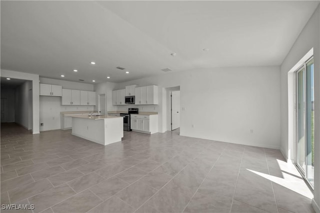 17620 Monte Isola Way N, Fort Myers, FL 33917 - kitchen featuring appliances with stainless steel finishes, open floor plan, white cabinets, a kitchen island with sink, and recessed lighting