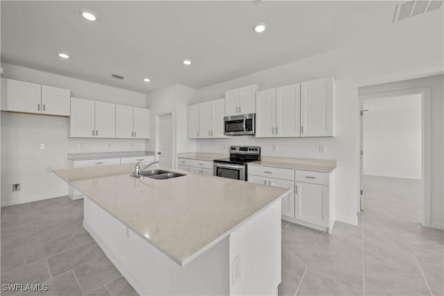 17620 Monte Isola Way N, Fort Myers, FL 33917 - kitchen with stainless steel appliances, a kitchen island with sink, white cabinetry, recessed lighting, and light stone countertops