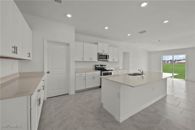 17620 Monte Isola Way N, Fort Myers, FL 33917 - kitchen with appliances with stainless steel finishes, white cabinets, light countertops, recessed lighting, and an island with sink