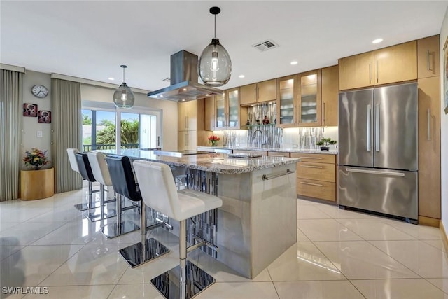 7105 Quail Run Ct W Unit 4, Fort Myers, FL 33908 - kitchen with freestanding refrigerator, island range hood, a kitchen island, light stone countertops, and brown cabinetry