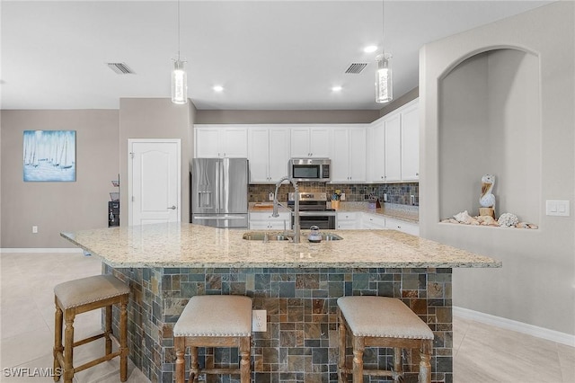 14659 Adina Ln, Fort Myers, FL 33905 - kitchen featuring appliances with stainless steel finishes, white cabinetry, light stone counters, decorative backsplash, and decorative light fixtures