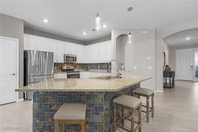 14659 Adina Ln, Fort Myers, FL 33905 - kitchen featuring appliances with stainless steel finishes, arched walkways, decorative backsplash, light stone countertops, and white cabinets