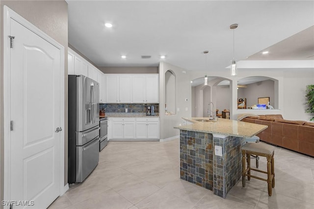 14659 Adina Ln, Fort Myers, FL 33905 - kitchen featuring appliances with stainless steel finishes, arched walkways, backsplash, light stone countertops, and white cabinets