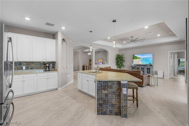 14659 Adina Ln, Fort Myers, FL 33905 - kitchen featuring arched walkways, open floor plan, ceiling fan, stainless steel fridge, and a tray ceiling