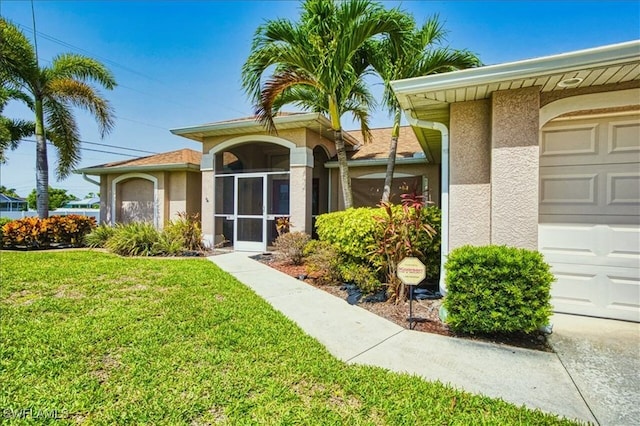 914 SW 9th Ct, Cape Coral, FL 33991 - view of exterior entry featuring stucco siding, an attached garage, and a yard