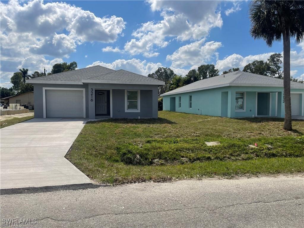 3220 Jeffcott St, Fort Myers, FL 33916 - view of front facade featuring an attached garage, driveway, stucco siding, and a front yard