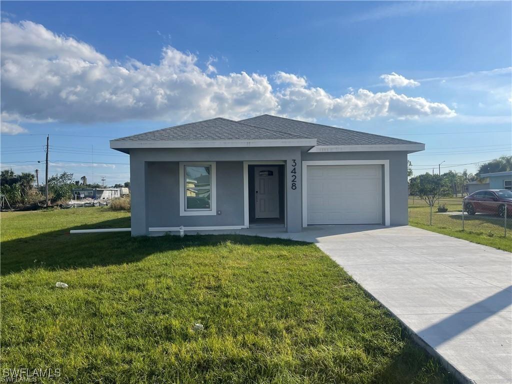 3220 Jeffcott St, Fort Myers, FL 33916 - view of front facade featuring a front lawn, an attached garage, concrete driveway, stucco siding, and a shingled roof