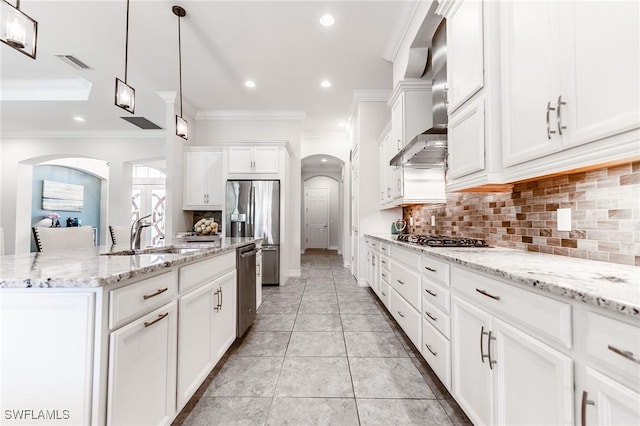 1387 Mockingbird Dr, Naples, FL 34120 - kitchen with arched walkways, wall chimney exhaust hood, appliances with stainless steel finishes, crown molding, and tasteful backsplash