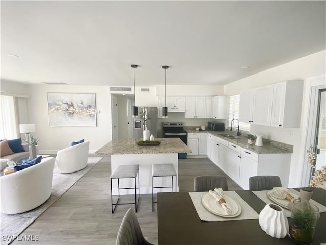 207 Leeland Heights Blvd W, Lehigh Acres, FL 33936 - kitchen with appliances with stainless steel finishes, a kitchen island, white cabinets, and wood finished floors