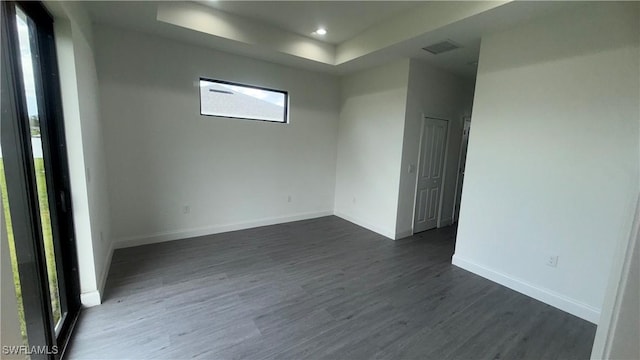 933 Gleason St, Lehigh Acres, FL 33974 - empty room featuring healthy amount of natural light, dark wood-type flooring, a tray ceiling, and recessed lighting