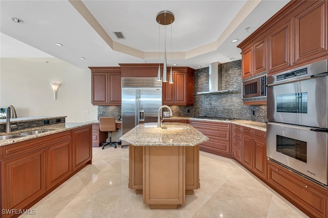 940 Cape Marco Dr Unit 1603, Marco Island, FL 34145 - kitchen with built in appliances, wall chimney range hood, a tray ceiling, decorative backsplash, and light stone countertops