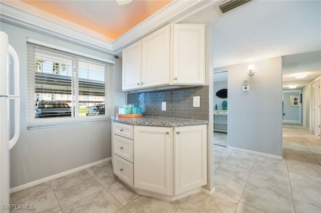 4549 SE 5th Pl Unit 109, Cape Coral, FL 33904 - kitchen featuring decorative backsplash, white cabinetry, light stone counters, light tile patterned floors, and freestanding refrigerator