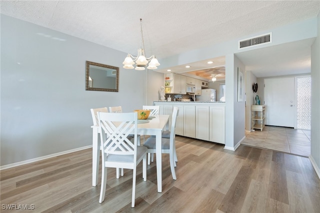 4549 SE 5th Pl Unit 109, Cape Coral, FL 33904 - dining area featuring a chandelier, light wood finished floors, and a textured ceiling